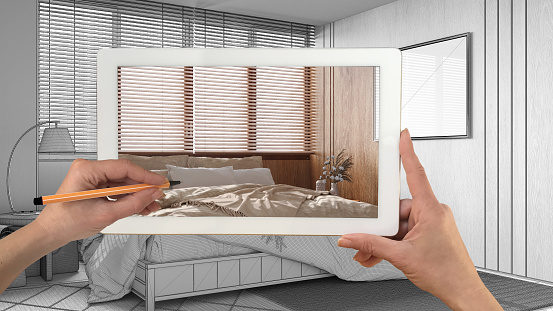 Augmented reality concept. Hand holding tablet with AR application used to simulate furniture products in custom architecture design, black ink sketch, minimal bedroom