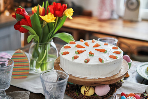 Colorful Decorated Easter Table with Easter Eggs, Flowers and Carrot Easter Cake