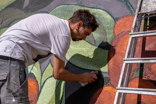 istock A graffiti artist paints graffiti on a large retaining wall. 1473542581
