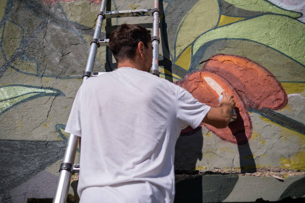istock A graffiti artist paints graffiti on a large retaining wall. 1473542608