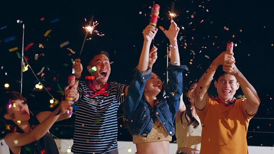 Group of young Asian people with friends celebrating party on rooftop holding sparklers fireworks and enjoy together