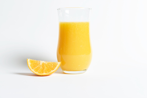 Glass of orange juice with sliced orange from above on white wooden background. fresh fruit product display.