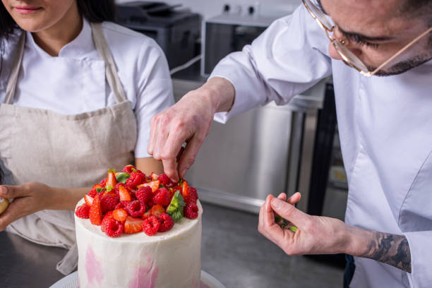 istock Two pastry chefs decorating a strawberry and raspberry cake. 1473547680