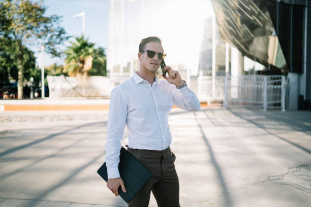istock Confident man with tablet talking on smartphone on street 1473551212
