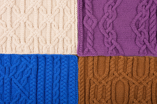 Knitted blue, lilac, brown, and beige background. Large knitted fabric with a pattern. Close-up of a knitted blanket. Banner