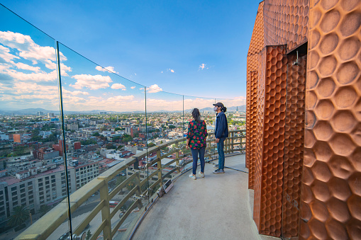 Ciudad de México - 01 de Abril de 2021: grupo de amigos mirando desde un pequeño mirador en el punto más alto del monumento a la revolución con un hermoso cielo soleado
