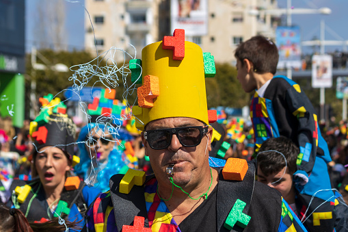 Limassol, Cyprus, February 19th, 2023:  Mature man in multi colored carnival costume taking part in Children’s Carnival Parade