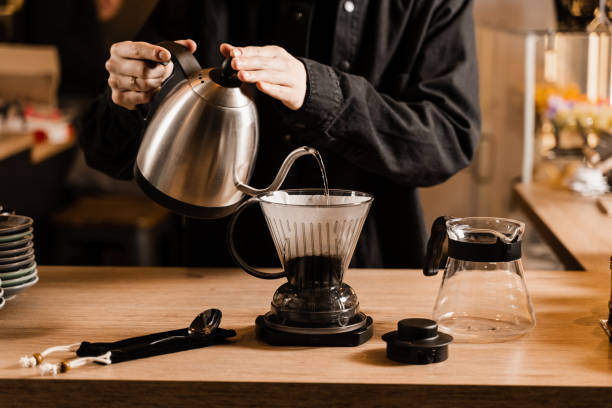istock Clever coffee dripper and pour over filter coffee alternative brewing method. Pouring hot water over roasted and ground coffee beans contained in paper filter. 1473554153
