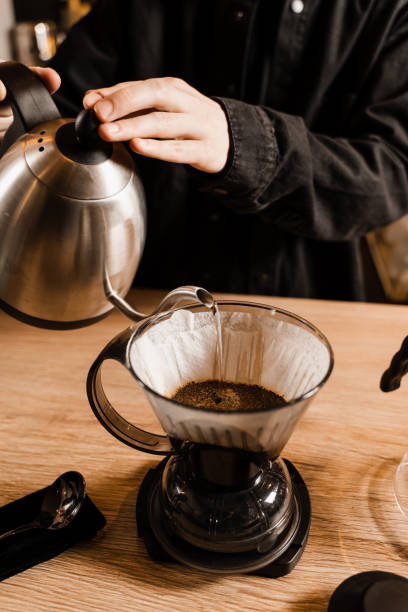 istock Clever coffee dripper and pour over filter coffee alternative brewing method. Pouring hot water over roasted and ground coffee beans contained in paper filter. 1473554168