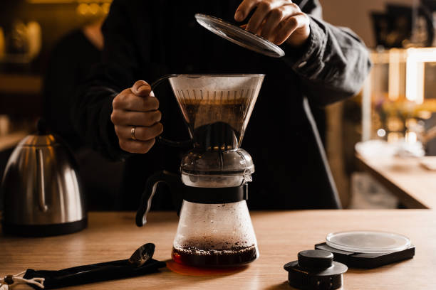 istock Process of brewing clever coffee dripper with pour over filter in cafe. Alternative method of brewing coffee in clever dripper at home. 1473554211
