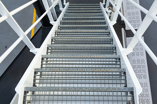 Ship's steel ladder with handrails leading down. Marine steel ladder on a ship.