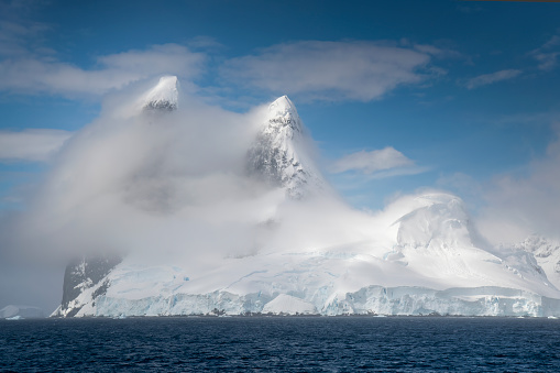 High winds create dramatic cloud formations in a polar landscape.