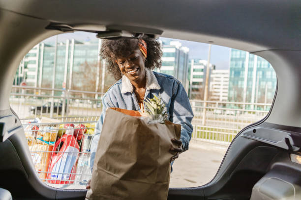 Smiling young African-American packing groceries in a car trunk