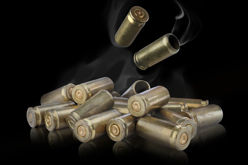 Cartridge cases with smoke falling onto other against black background