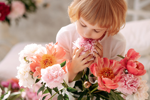 Young pregnant woman arranging beautiful yellow tulips in a vase.