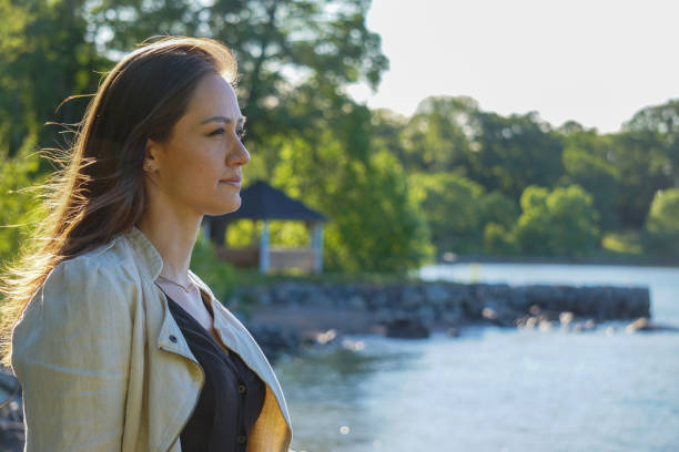 Young woman looking away while standing by lake