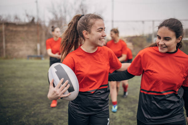 Group of women, female rugby team on rugby field together outdoors.