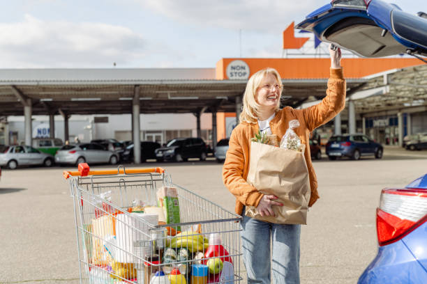 istock Woman smiling while loading her trunk with groceries 1473574860