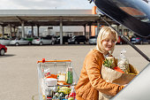 Woman putting groceries in her car on a parking lot