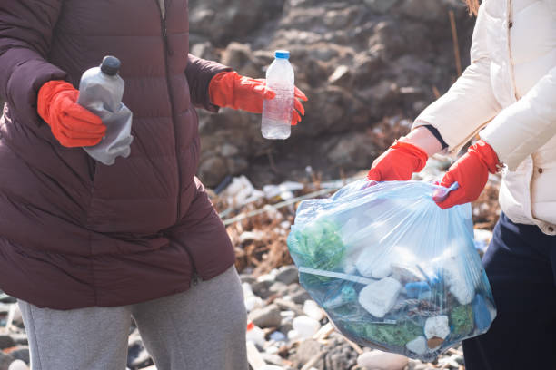 istock two woman collects plastic garbage in bags on the beach. pollution disaster. Empty plastic bottles 1473574941