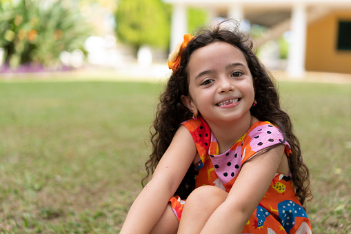 Portrait of beautiful girl sitting on grass at farm