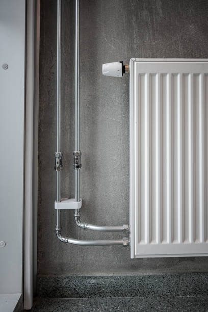 istock Heating pipes and radiator on a concrete wall.. 1473575920