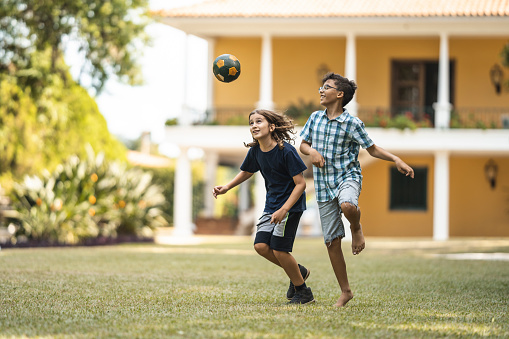 Kids playing with soccer ball on grass outdoors