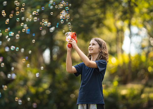 Boy playing with bubbles in public park