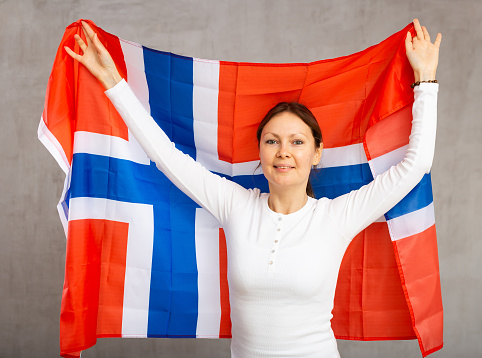 Cheerful smiling woman posing proudly with flag of norway