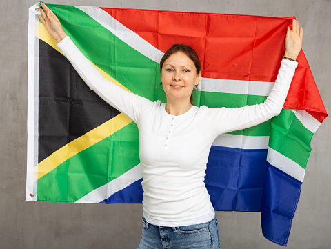 Cheerful adult woman holding big South African Republic flag in her hands