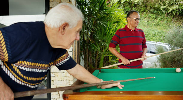 istock Smiling senior men playing pool outside on a patio 1473577584