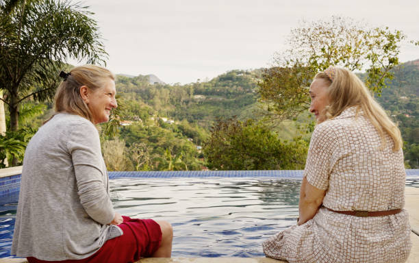 istock Smiling senior women talking while relaxing with their legs in a swimming pool 1473577585
