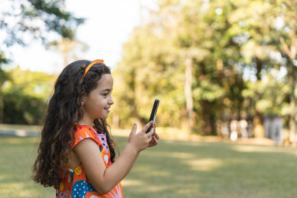 istock Small girl using smartphone outdoors 1473578372
