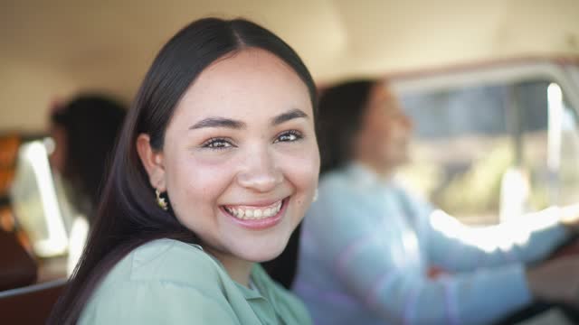 Portrait of young woman sitting on co-pilot seat on a road trip in retro mini van