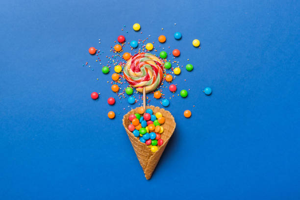 istock waffle cone full of assorted traditional candies falling out on colored background with copy space. Happy Holidays sale concept 1473591184