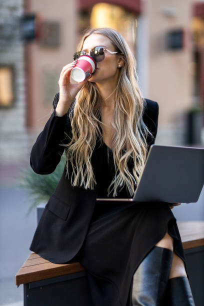 istock business woman on bench with laptoop and coffee in hand 1473601085