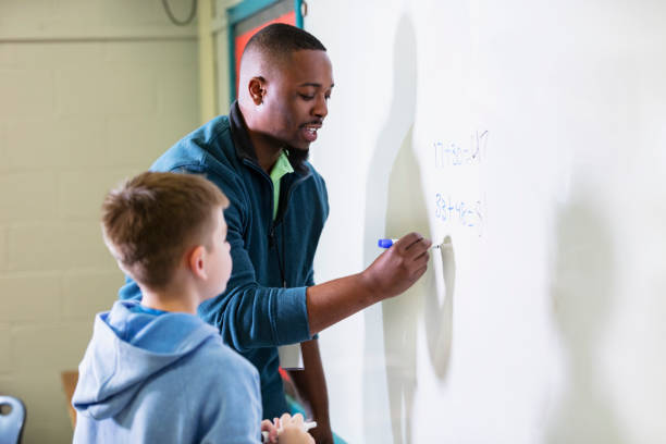 istock African-American math teacher at whiteboard with student 1473601248