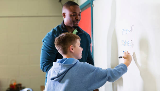 istock Boy in math class with male teacher at whiteboard 1473601260