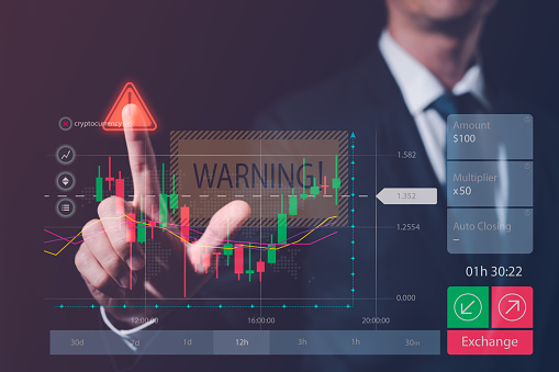 trading investment alert concept, businessman or trader with virtual trading graph and warning alert sign, investment in economy crisis