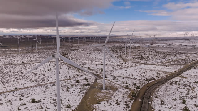 Row of Wind Turbines in Snowy Desert Landscape - Drone Shot