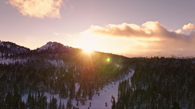 Ascending Drone Shot of Snowy Mountain Slope Revealing Setting Sun