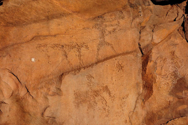 istock Rock paintings by ancient artists on a flat red stone close-up. 1473604164