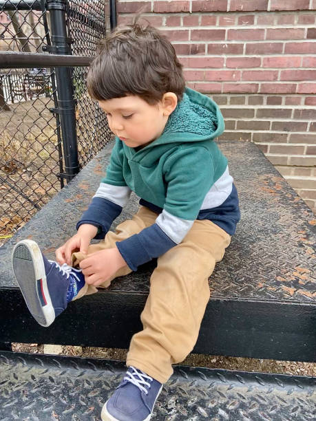 istock Toddler sitting tying a shoe lace on his sneaker 1473604171