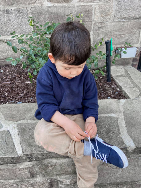 istock Toddler sitting tying shoes 1473604907
