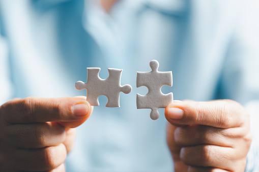 Business woman person hand holding puzzle piece idea for strategy and solution. Closeup part of two white jigsaw connect together. Concept of join cooperation success teamwork-problem corporate team