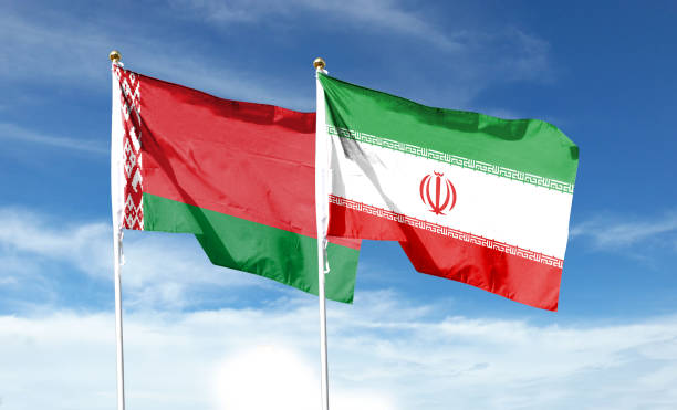istock Iran flag and Belarus flag on cloudy sky. waving in the sky 1473606992