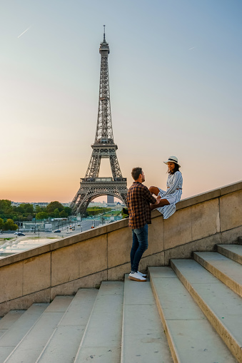 Young couple by Eiffel tower at Sunrise, Paris Eifel tower Sunrise man woman in love, valentine concept in Paris the city of love. Men and women visiting the Eiffel tower.