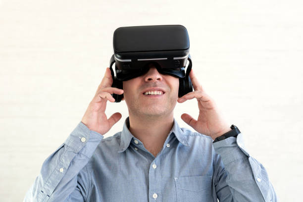 istock Young smiling man wearing tshirt and virtual reality headset or VR glasses, playing video game, white background 1473614455
