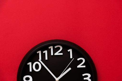 Black wall clock on red background.