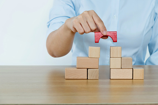 Businesswoman built a bridge with wooden blocks.